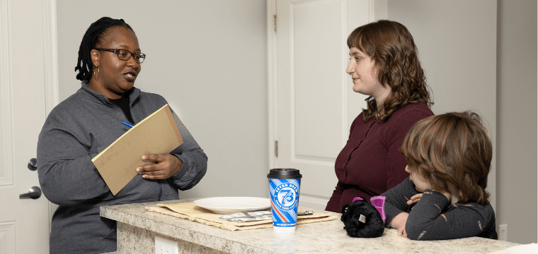 A case manager at Home for Families conducts a home visit with a client and her son