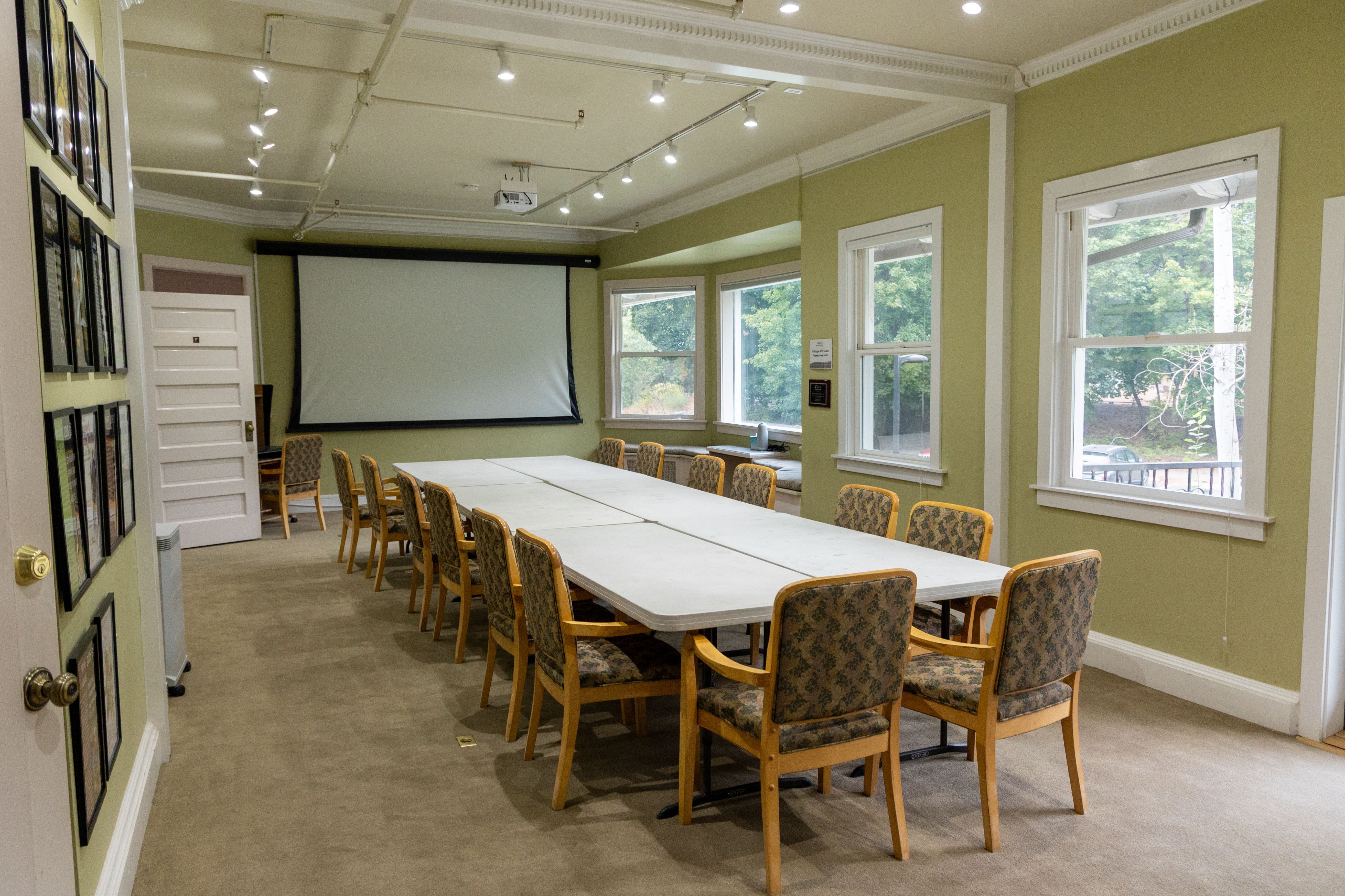 An image of the Bird Fest Room set up with tables and chairs facing a screen for a conference-style event layout.