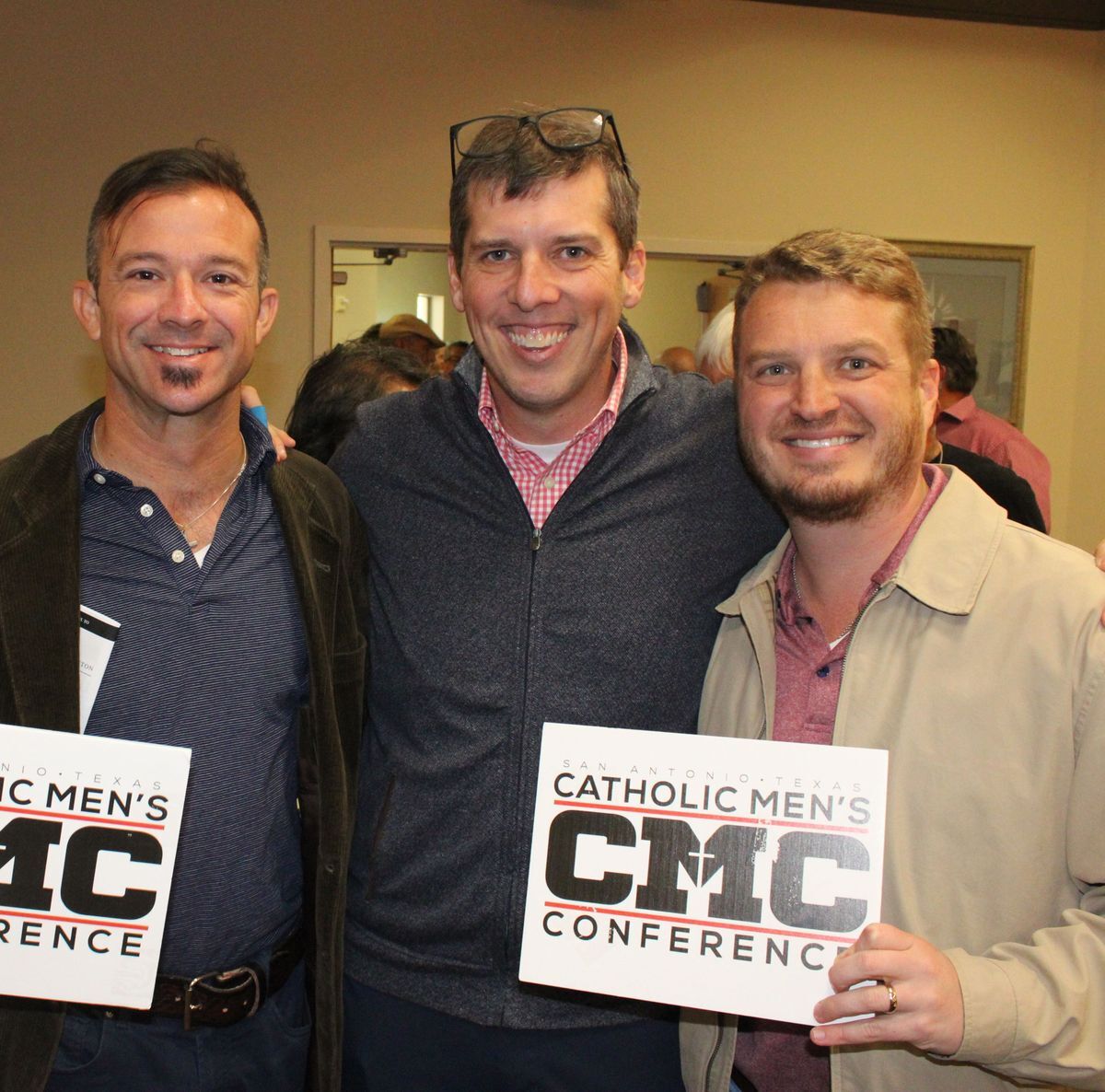 Men friends smiling together pose for a group photo holding logo signs at the conference