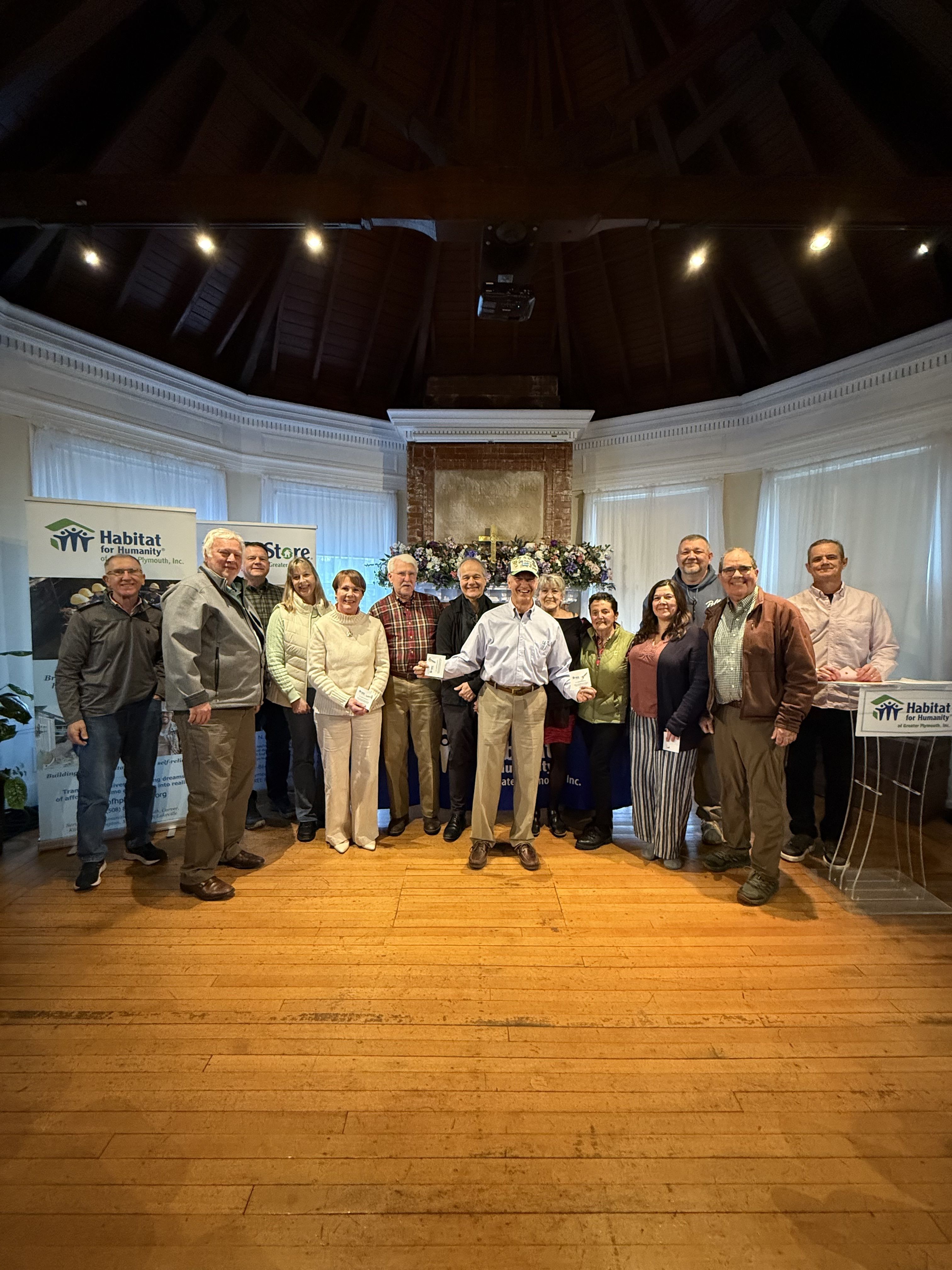 A group of Habitat volunteers sit in a window space on a new construction home site