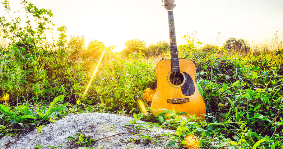Guitar in green meadow with rays from setting sun behind