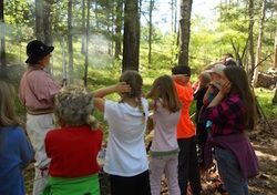 Children in the woods listening to teacher.
