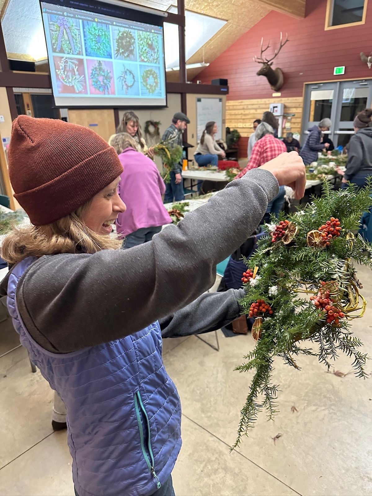 A woman proud of a holiday wreath made in WRI's Red Barn