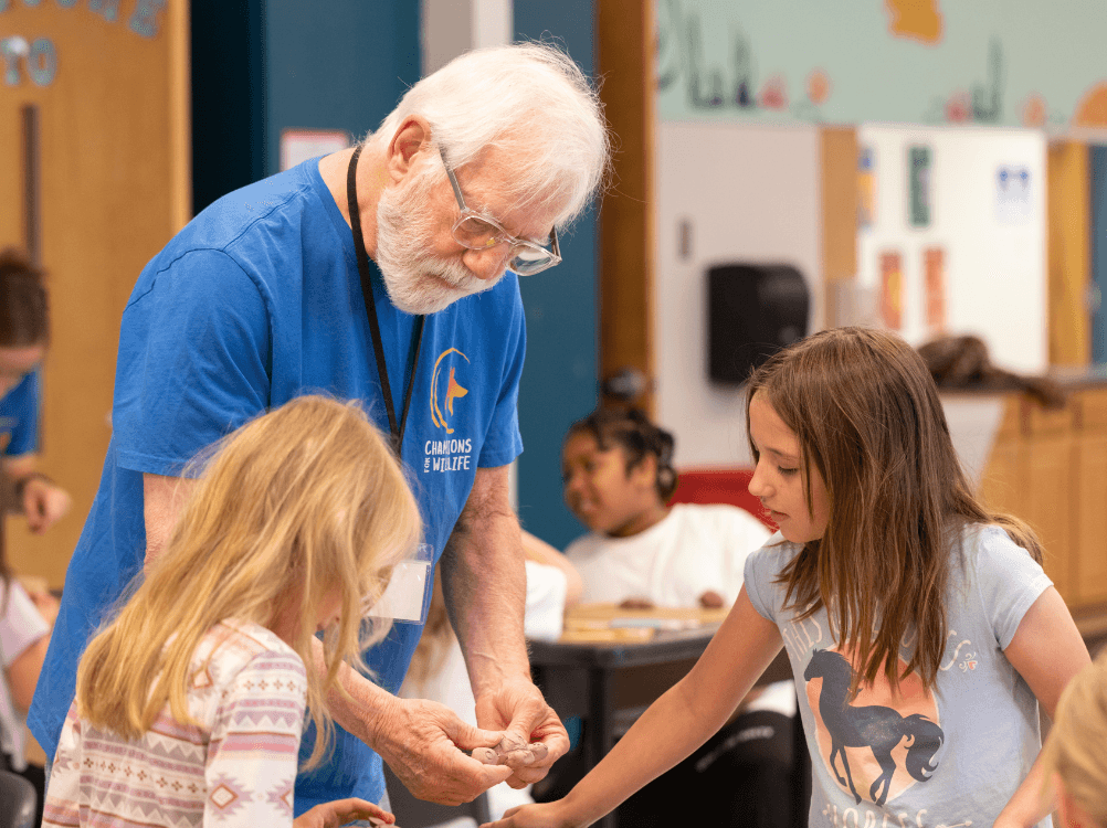 Volunteer helping students to work with clay