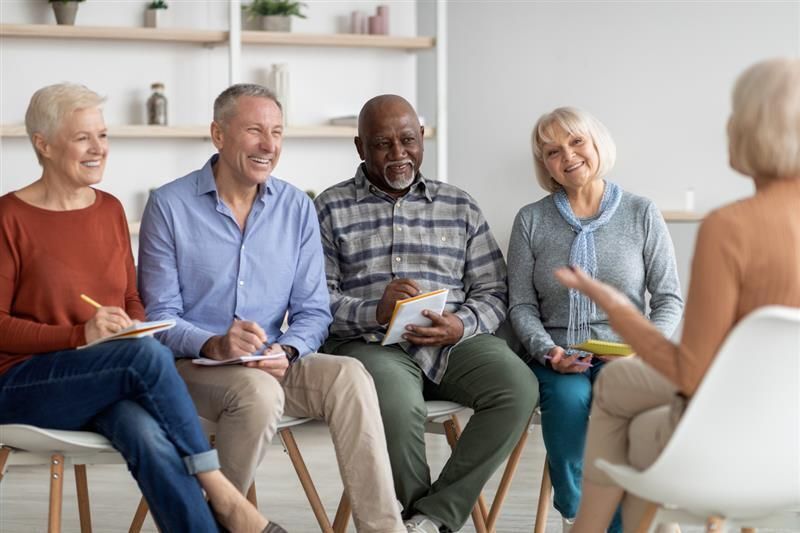 a group of adults sitting in a circle taking notes and chatting