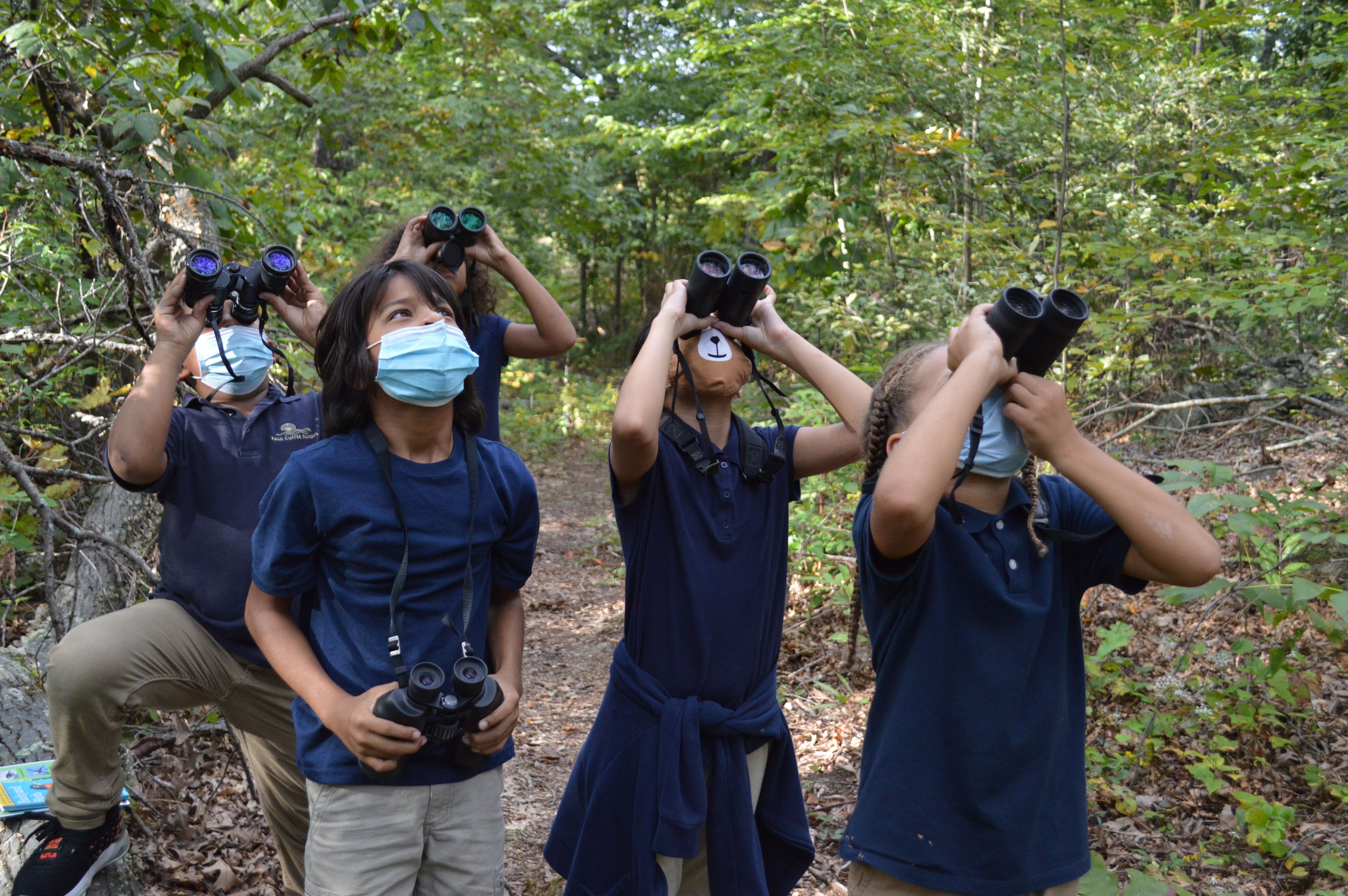 Paul Cuffee Elementary School look through their binoculars in the field at Neutaconkanut Hill Park