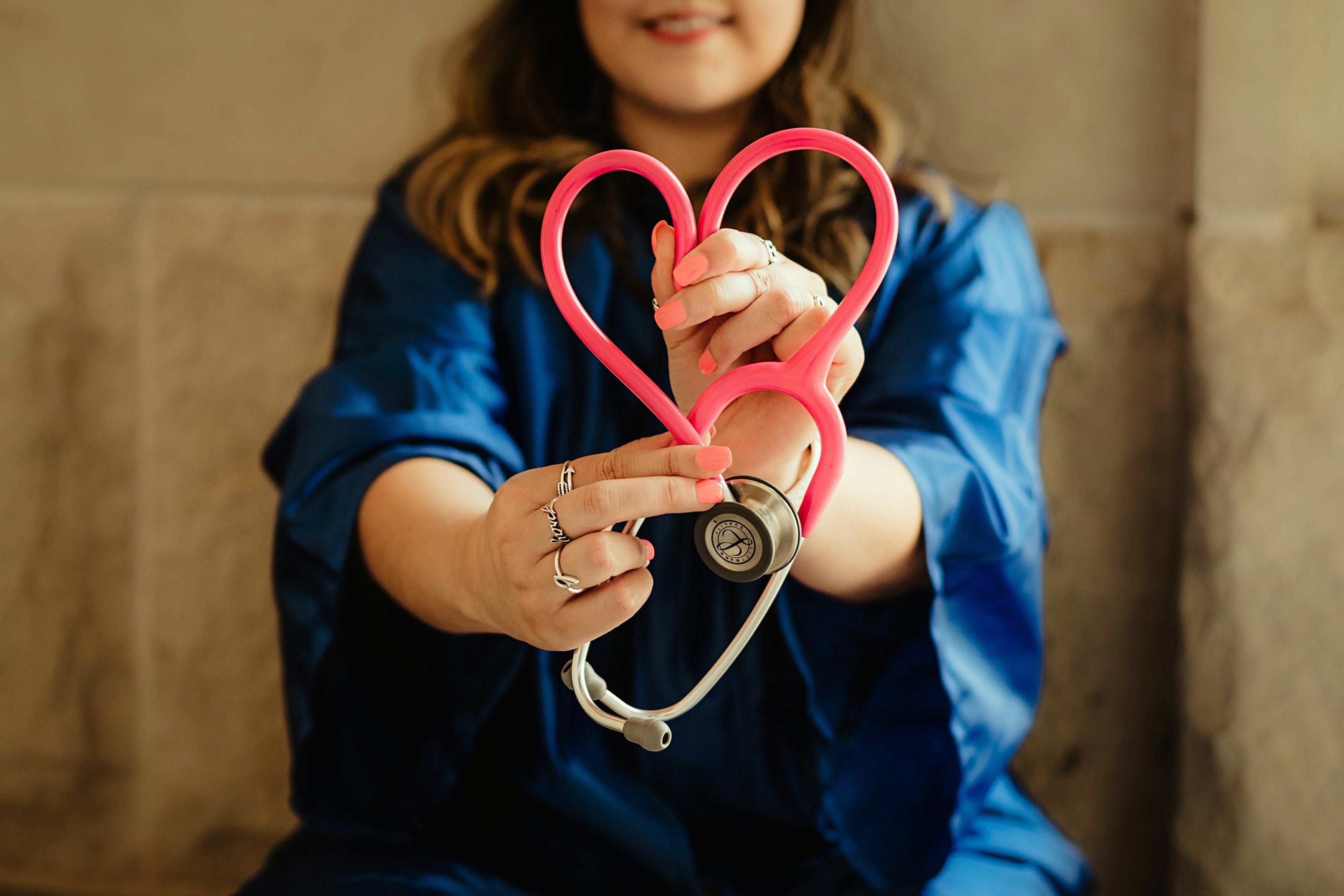 Photo of a nurse holding a stethoscope in the shape of a heart.