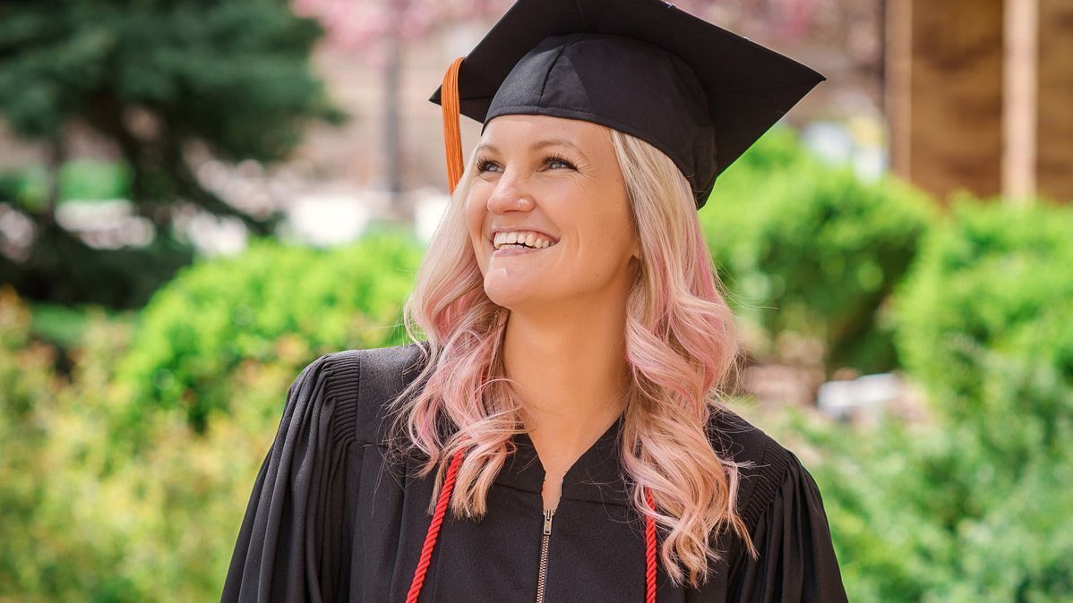 A female scholarship recipient wears a graduation cap and gown