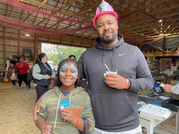 A father and daughter pose for a photo in Snipes Farm's Big Red Barn