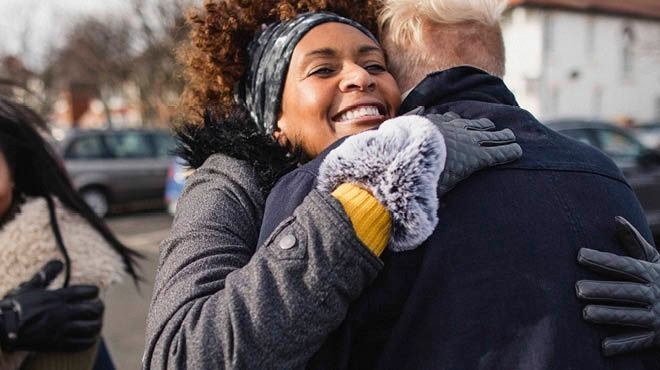 two people happily hugging on the street on a cold day