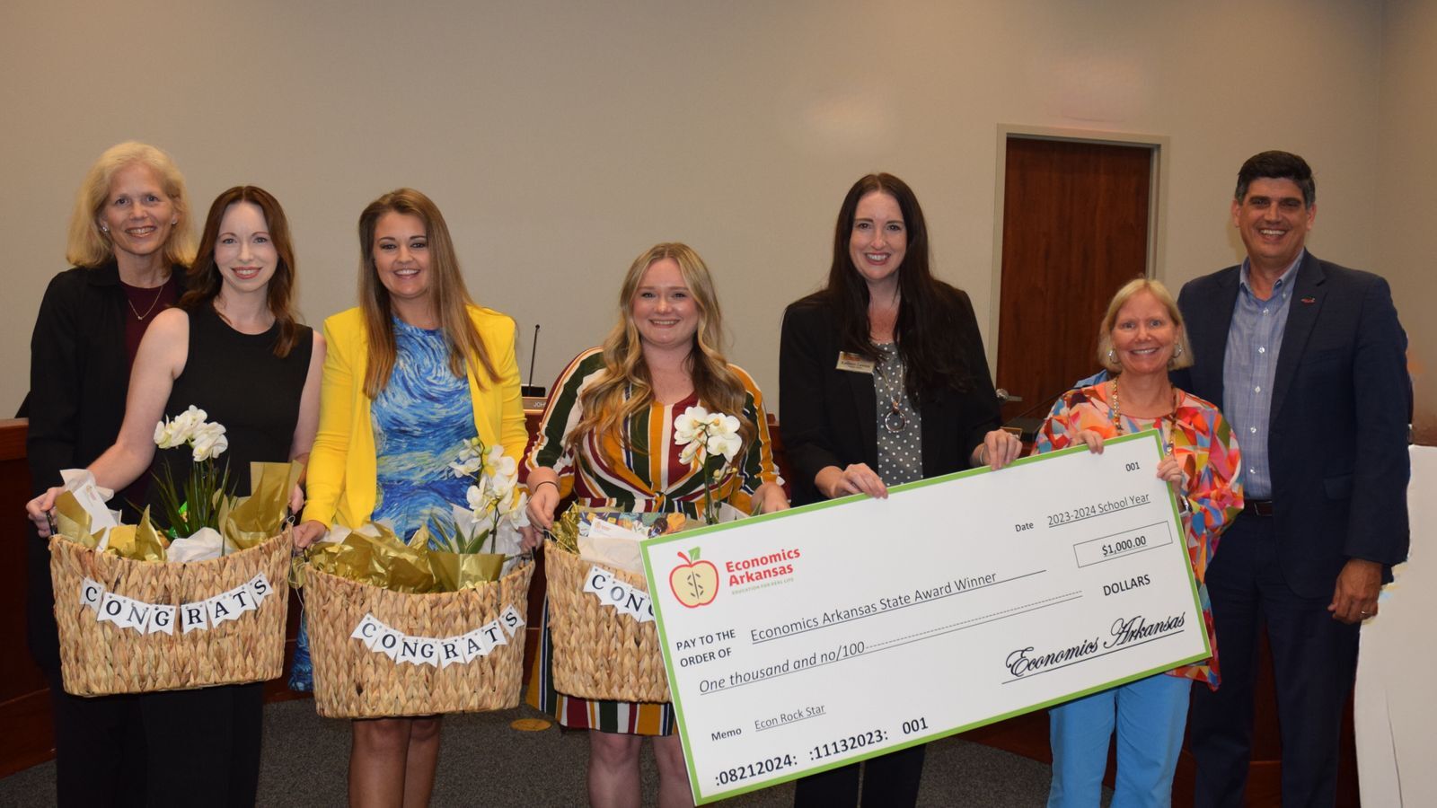 group of adults presenting large check and award to teachers