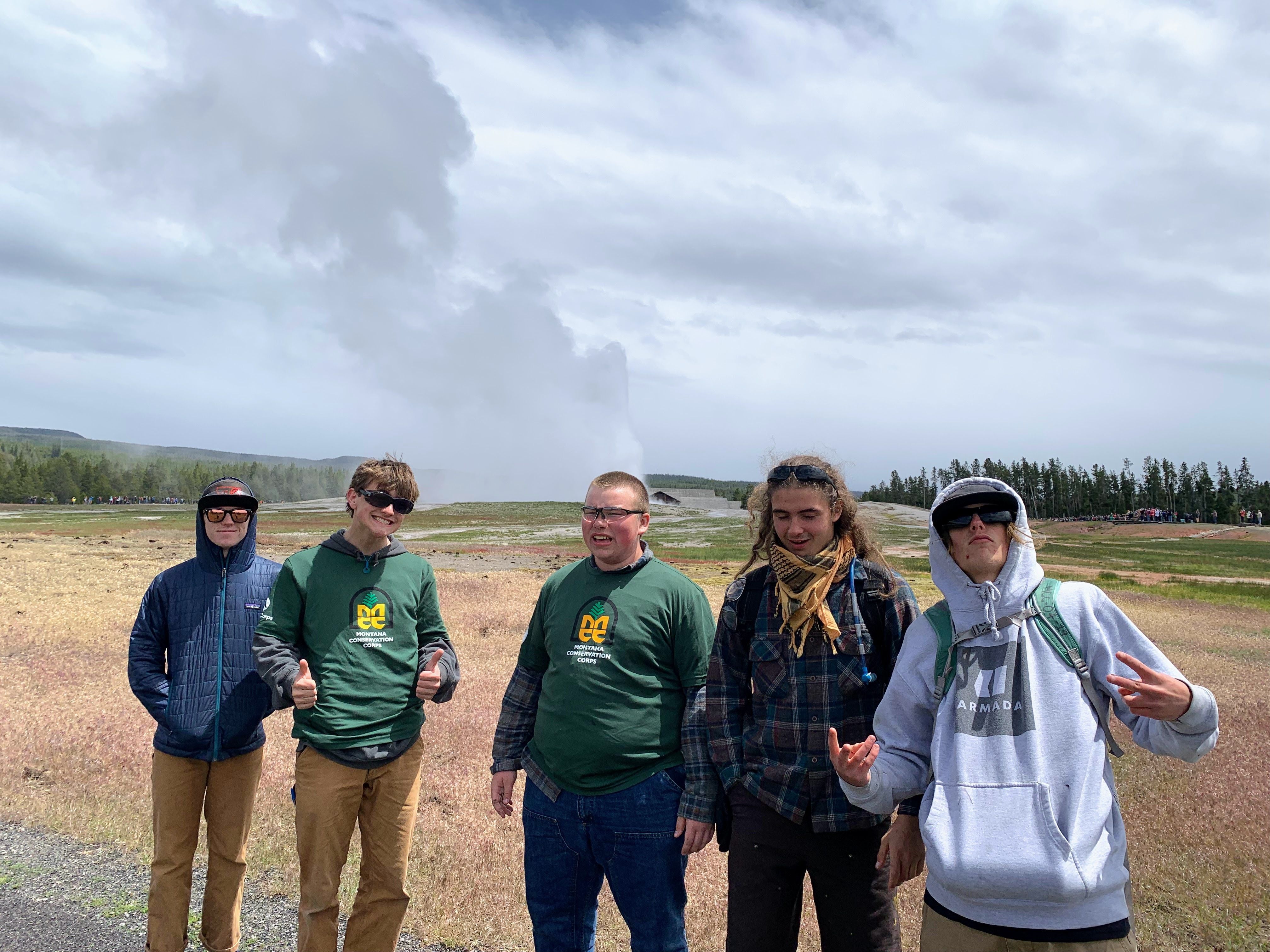 A youth crew stands next to a geyser.