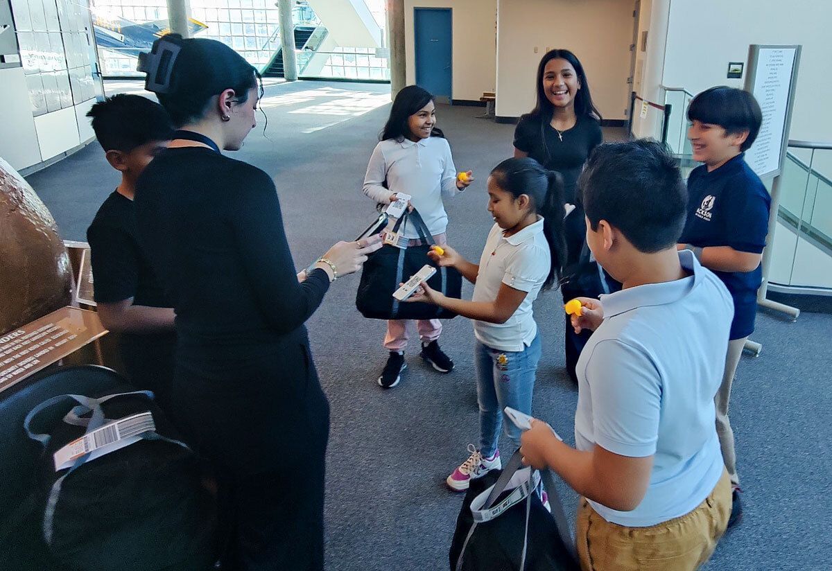 Students participating in the AI in the Airport STEM program at the Cradle of Aviation Museum, working in groups to explore how artificial intelligence is used in aviation.