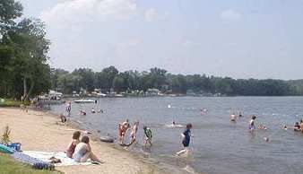 People sitting on the beach on Thornapple Lake. 