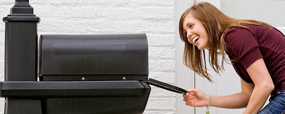 Woman eagerly looking inside an open mailbox.