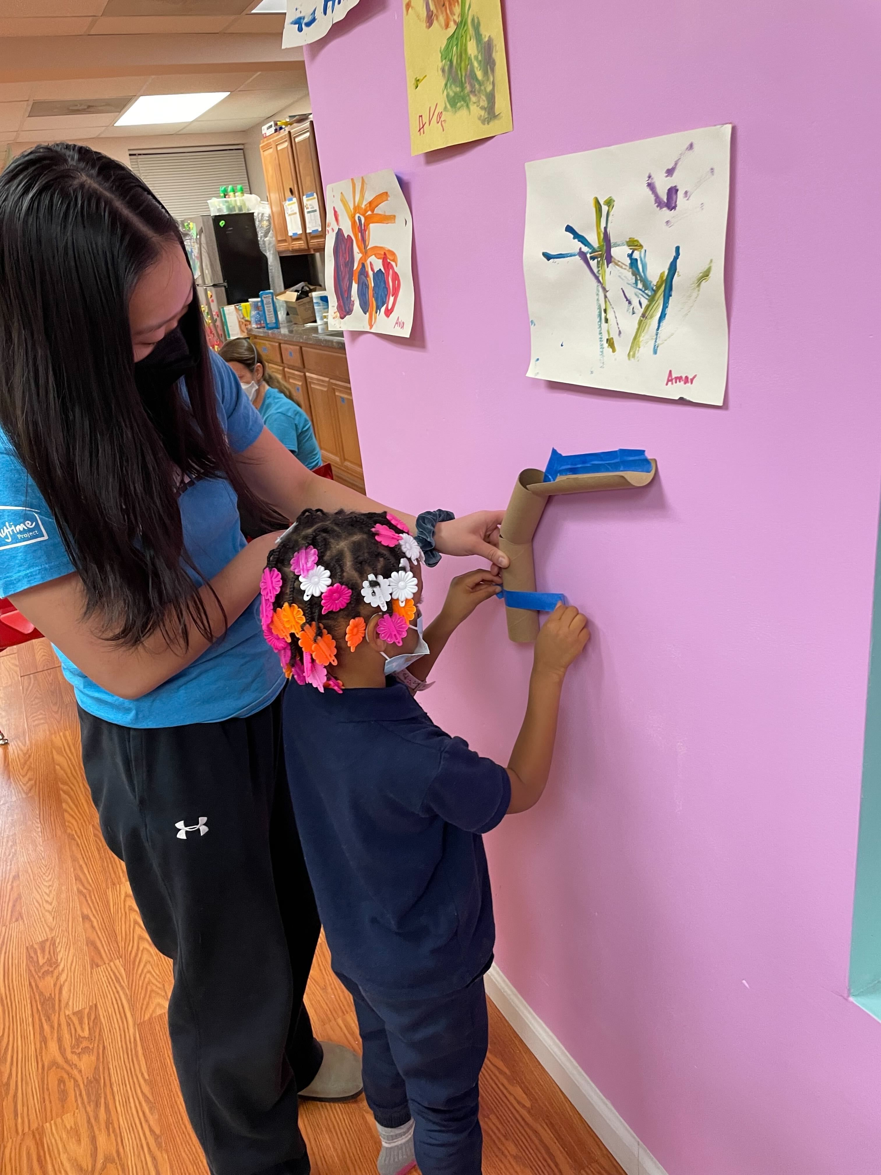 A Playtime volunteer and child work together to complete an activity.