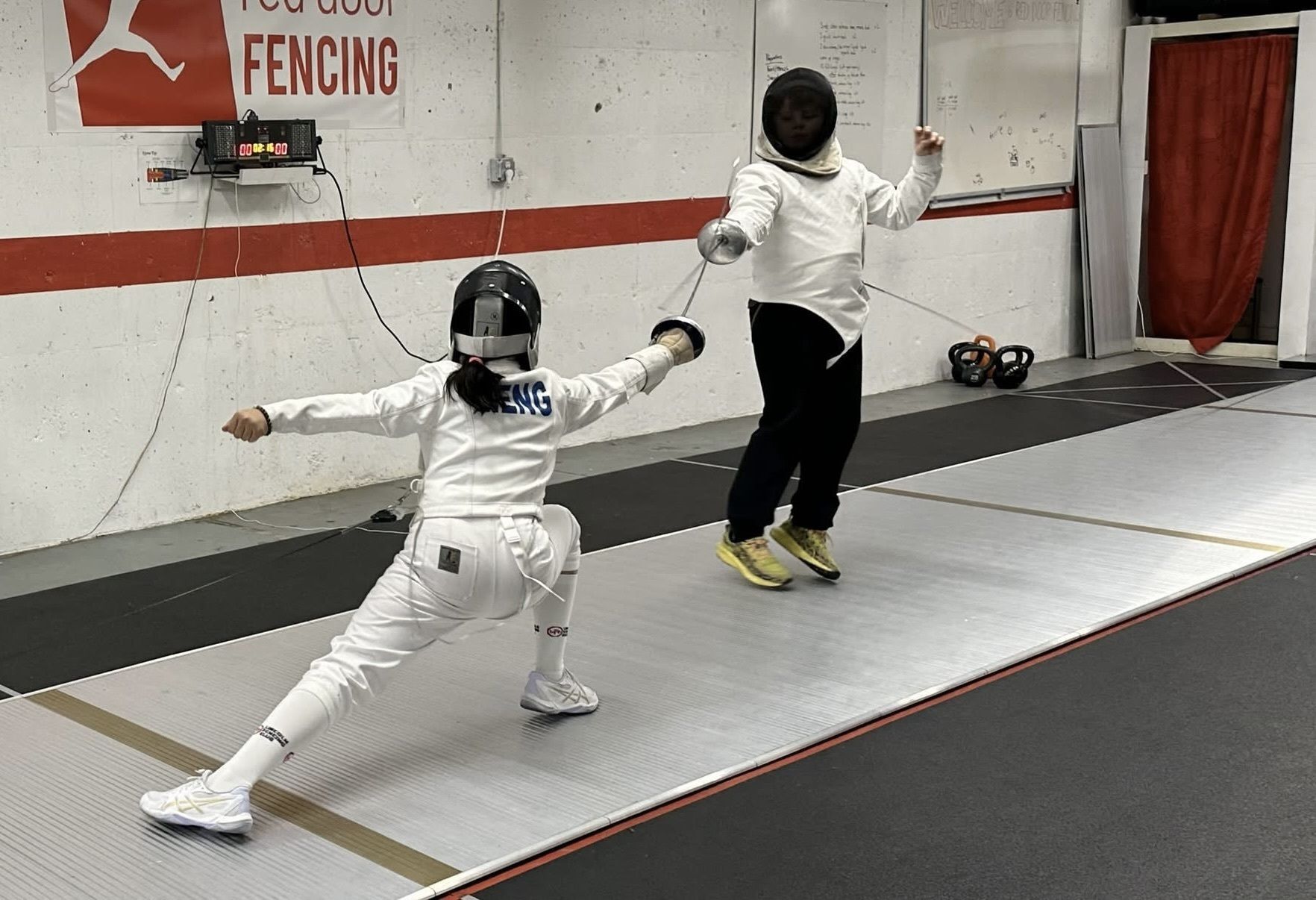 A youth fencer lunges at her opponent