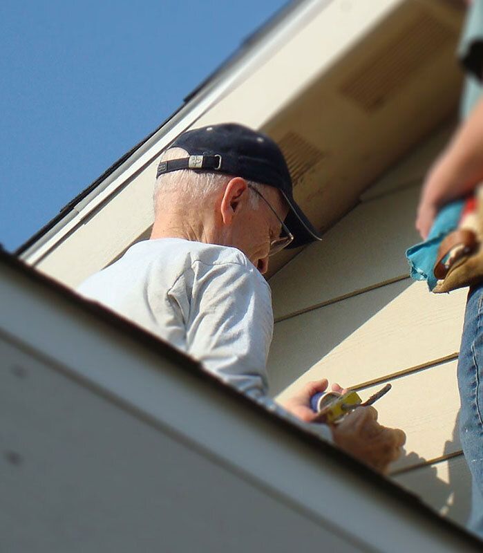 Man measuring the siding on a house.