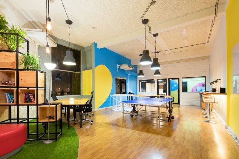 Creative office branding ideas utilizing blue and yellow office wall graphics to define a functional, energetic employee recreation workspace.