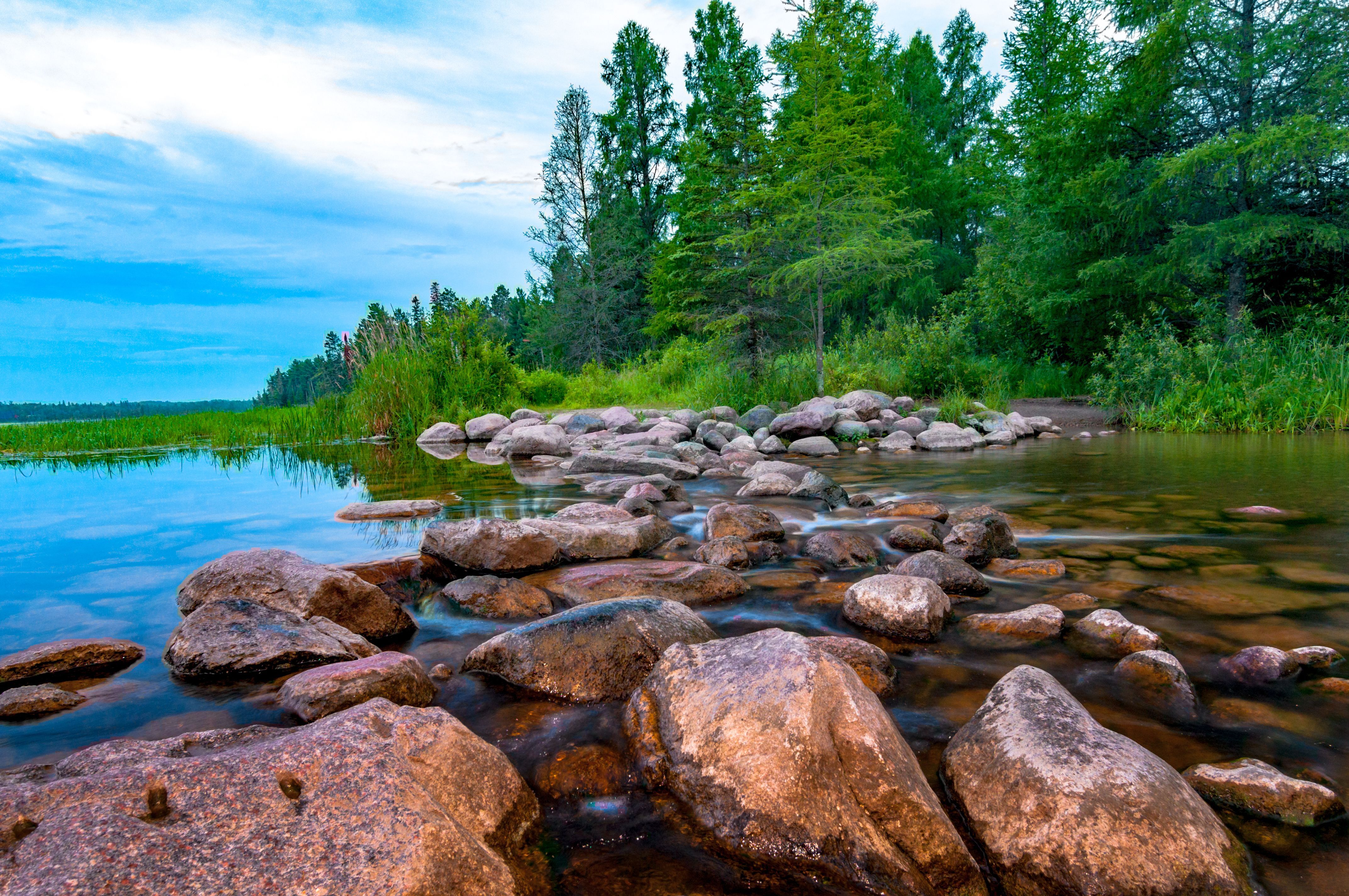 Headwaters of the Mississippi. Rocks down the center with a lake on one side and trees on the other.
