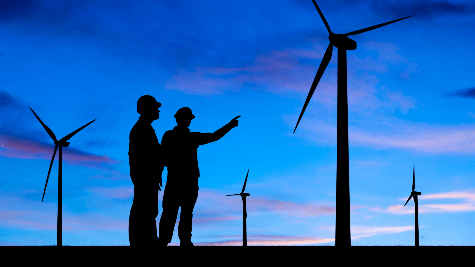 Two workers outlined in front of wind turbines