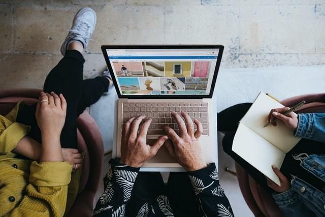 Three people huddle around a laptop for training.