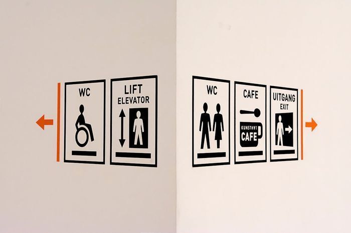 Minimalist wayfinding signage design featuring high-contrast black and white restroom and elevator icons to ensure clear facility navigation.