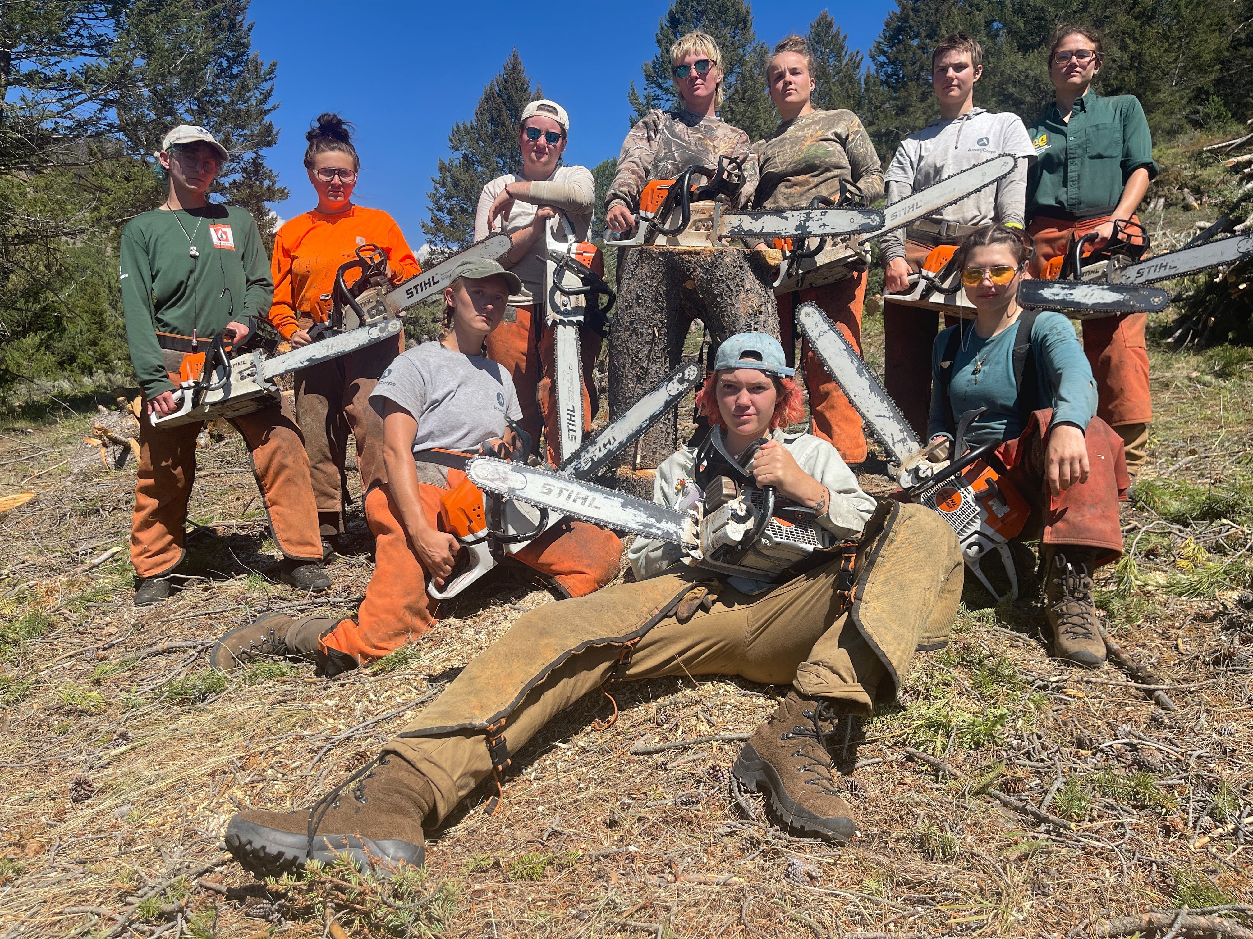 The women's fuels and fire crew all poses with their saws and full gear, fierce looks on their faces.