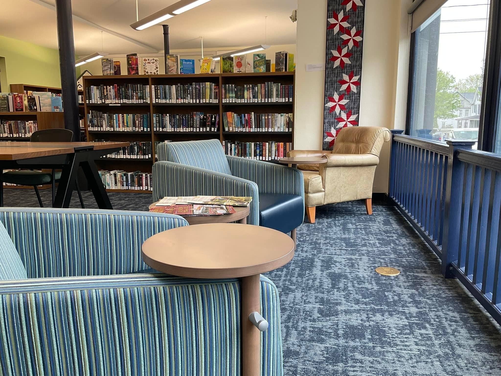 Two comfortable chairs face the bright windows in the Young Adult section.
