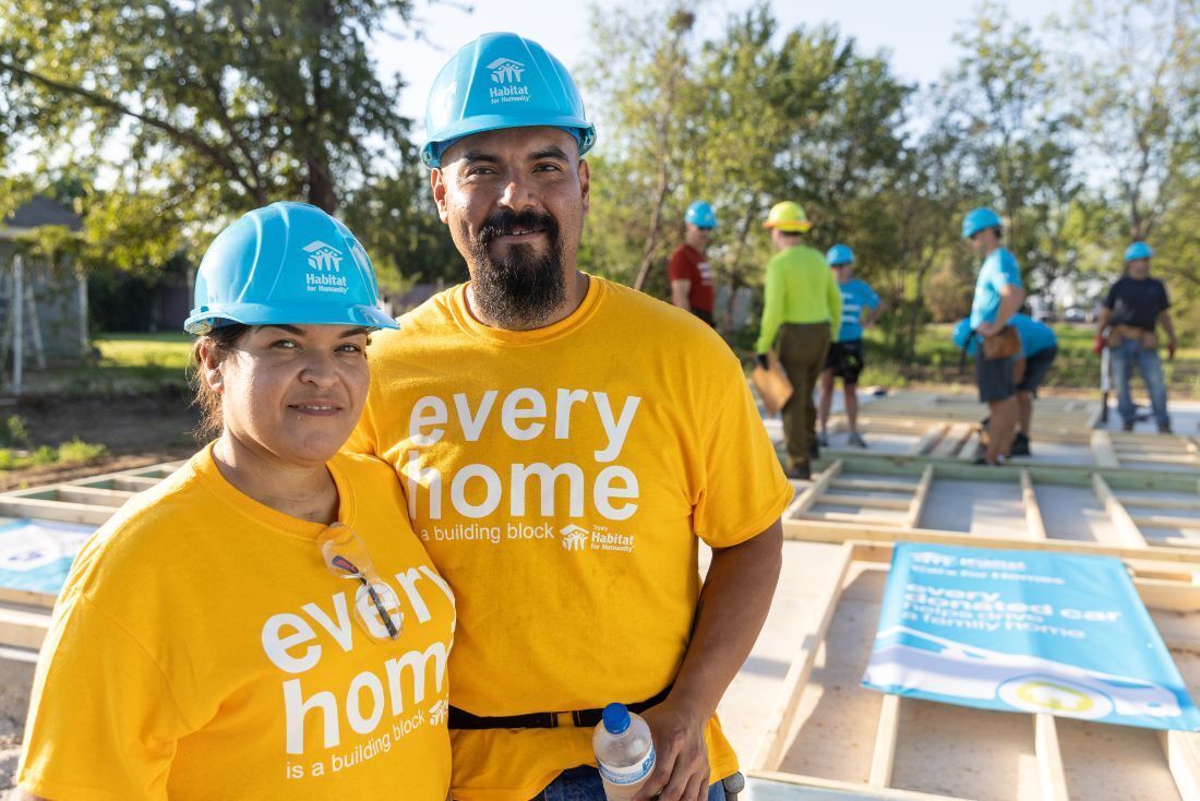 Volunteers wearing yellow shirts with text Every Home is a building block.