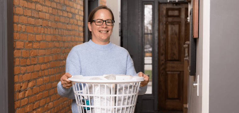 A case manager at Home for Families holds a baby basket with items for newborns for new moms