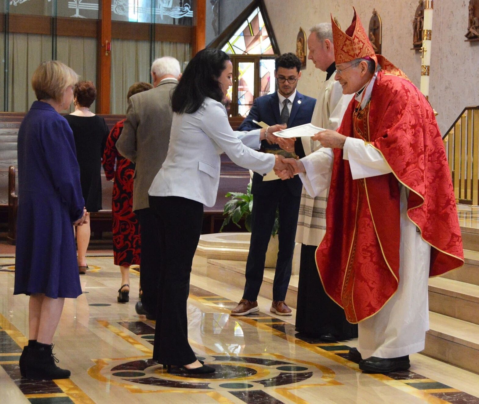 A woman receives her School of Christian Formation certificate of completion from Bishop Gerald M. Barbarito May 14, 2025.