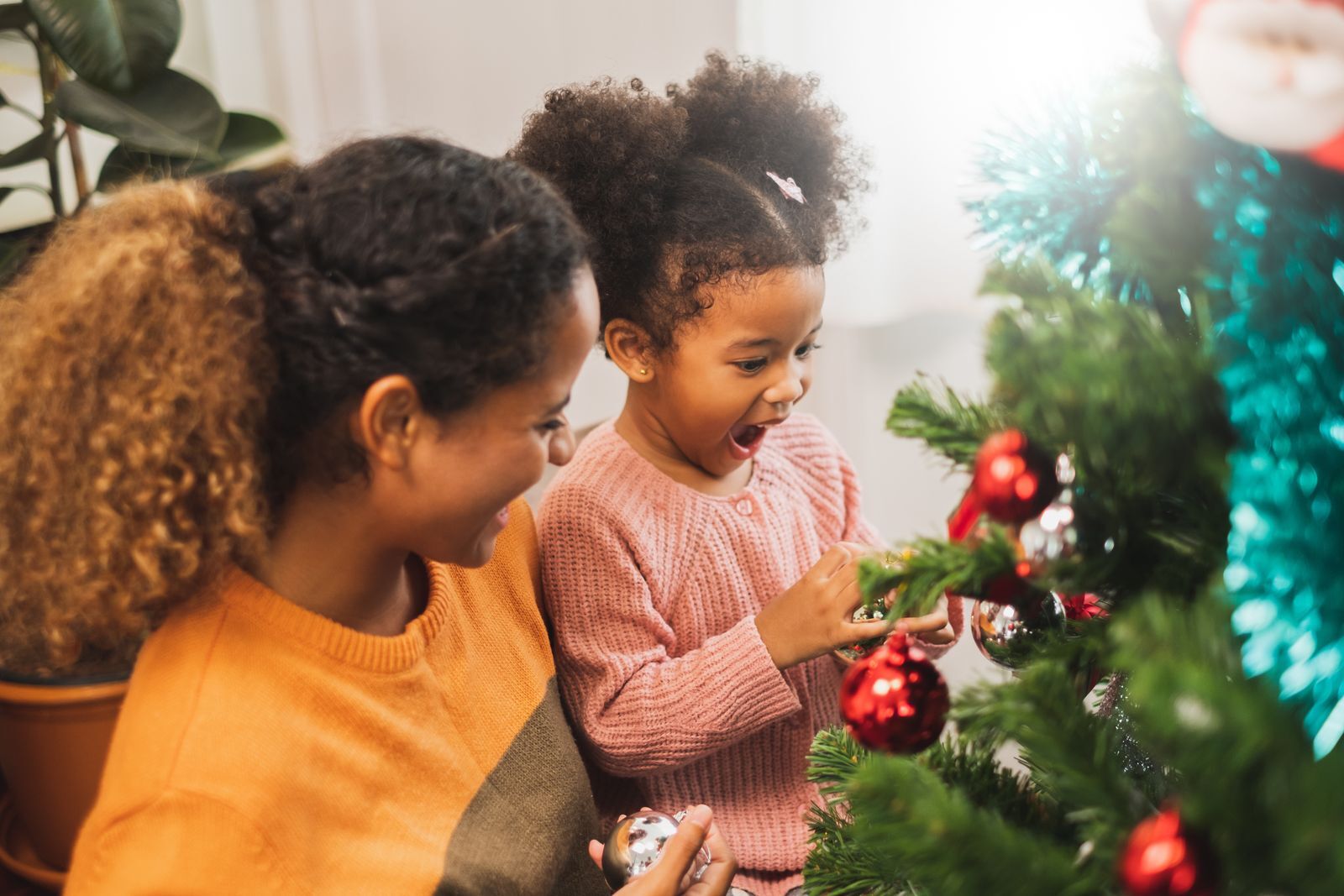 picture of young girl decorating holiday tree with her mother