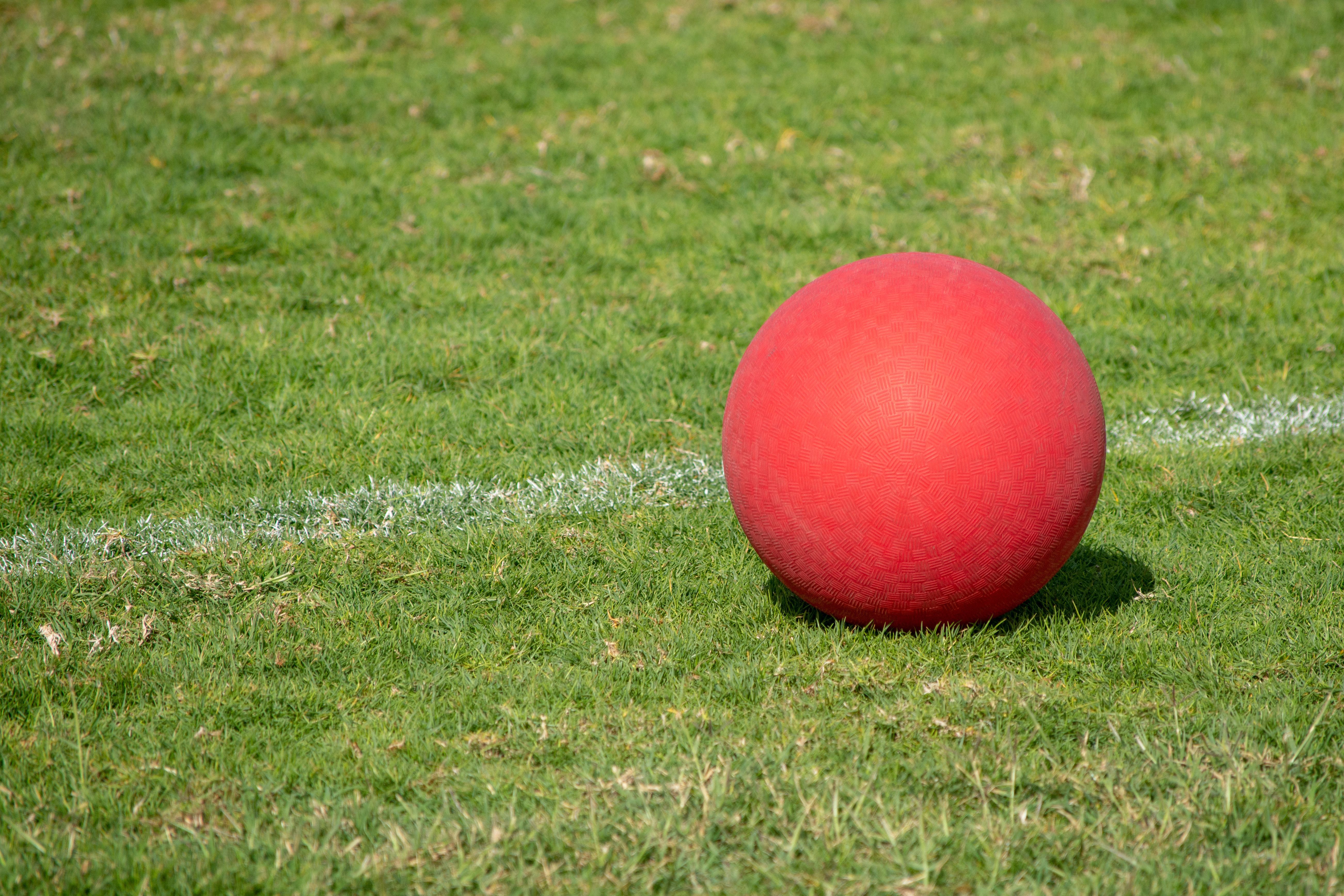 A red kickball on a greenn grass field