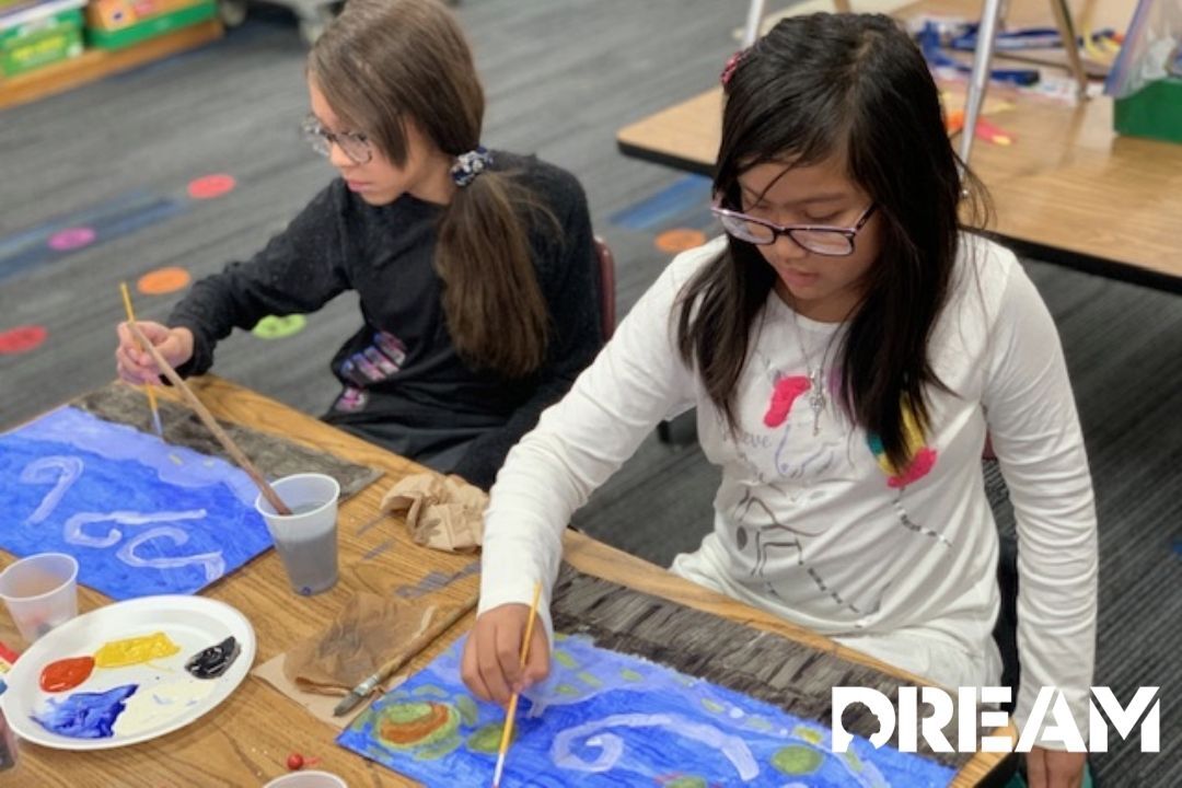 A couple kids painting while sitting at a table