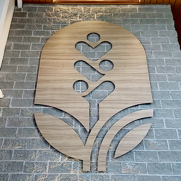 Dimensional interior sign with wood-grain finish mounted on a brick wall, designed and installed by Keen Signs and Graphics in Augusta, GA