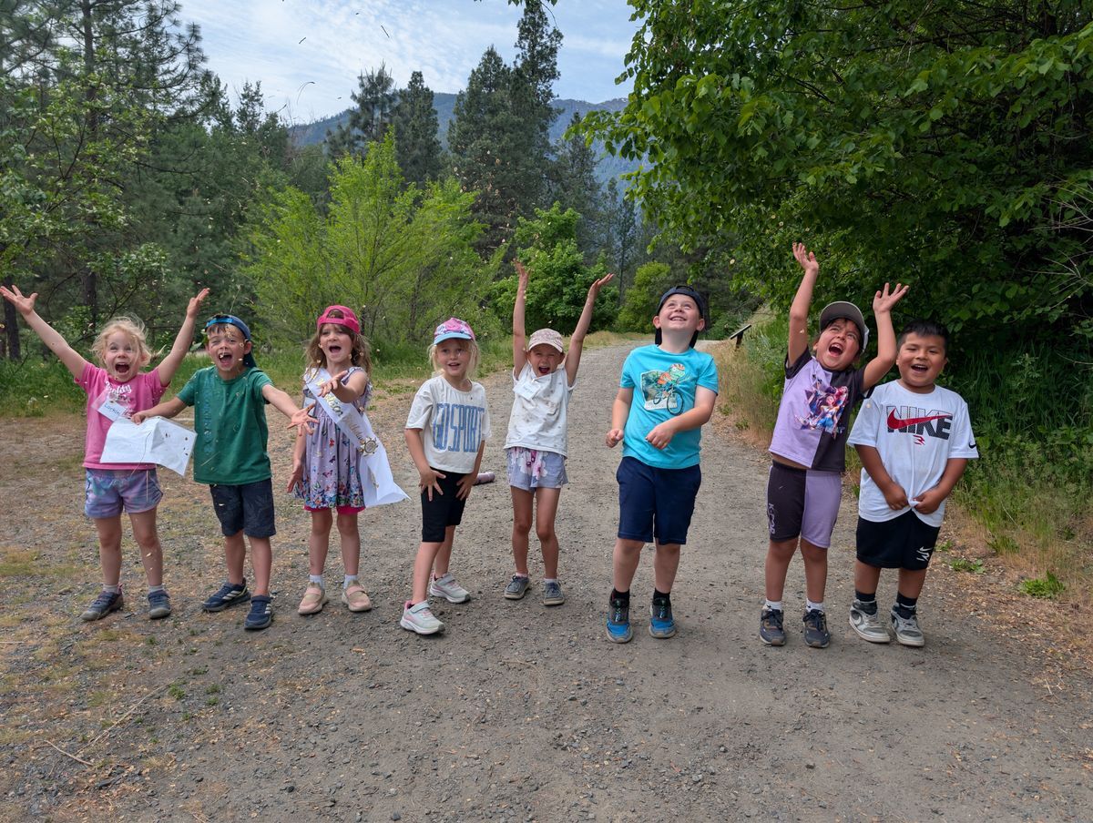 A group of kindergarteners lined up on the trail smiling at the camera.
