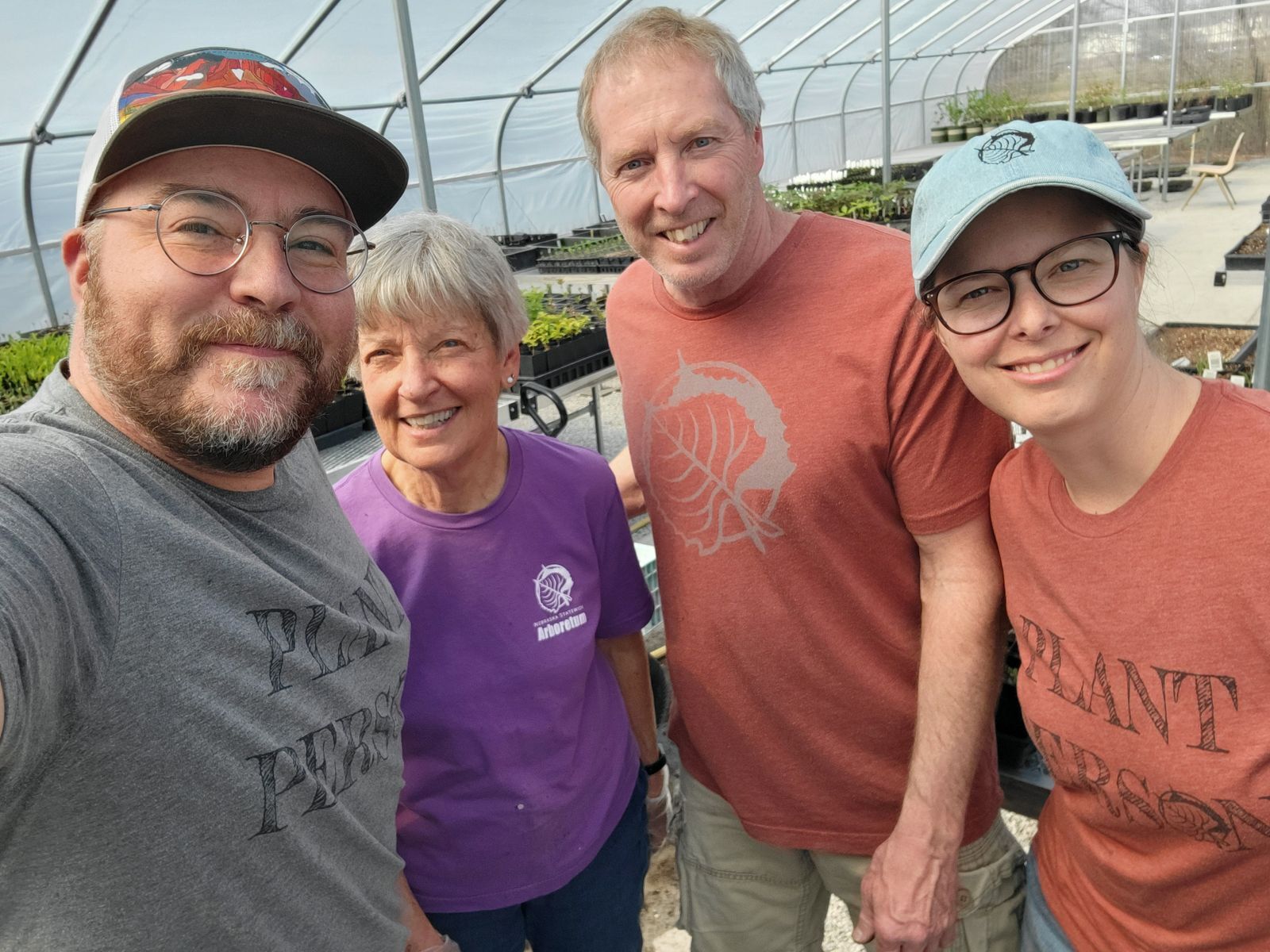 Two men and two women volunteers in the greenhouse.
