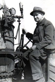 Black and white photo of an elderly Irving Delos Charlton on 1884 Westinghouse steam engine.