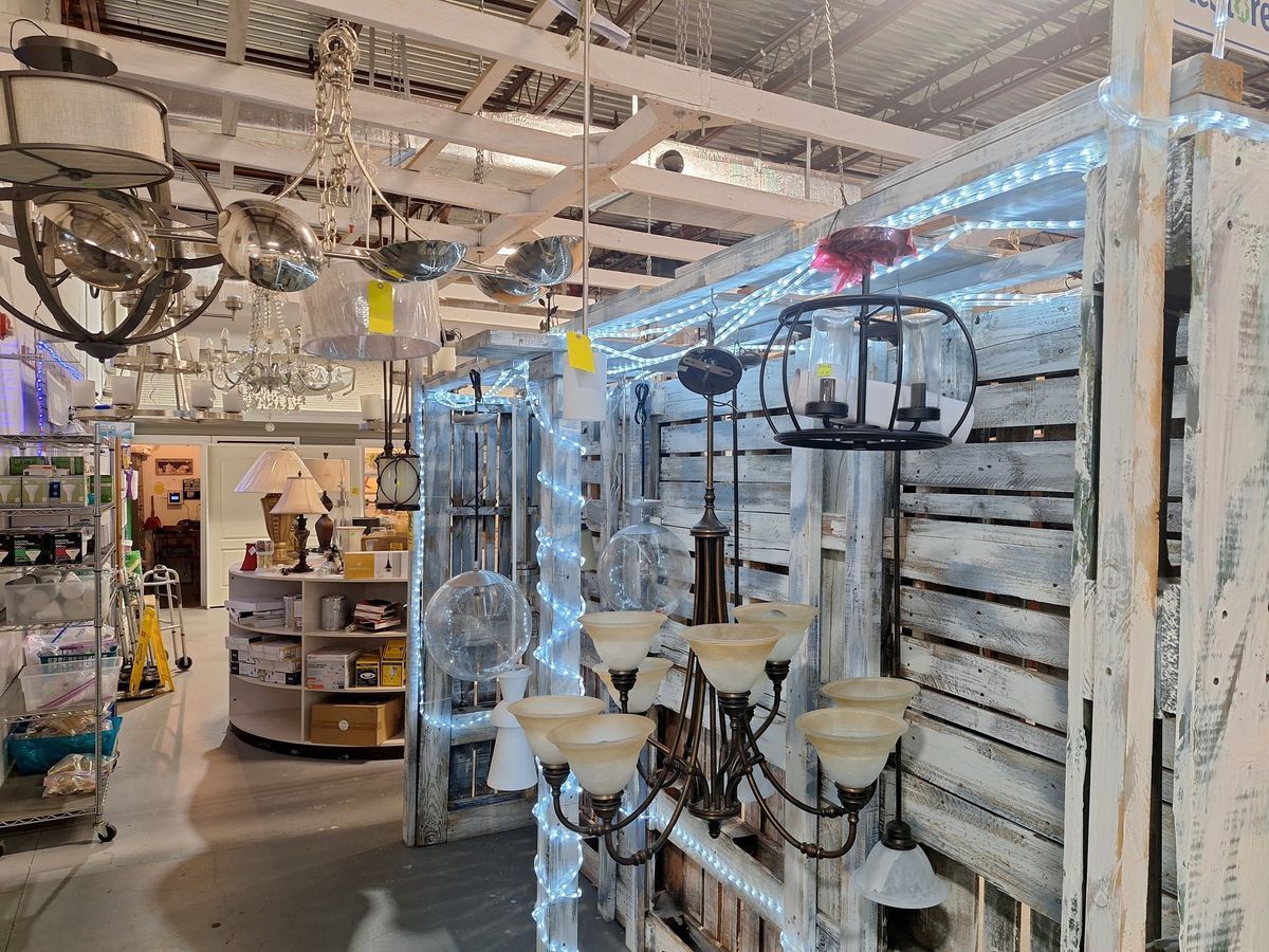 Assorted ceiling lights, hanging chandeliers, and pendant fixtures on display at Habitat ReStore Zephyrhills lighting department, including modern and vintage styles