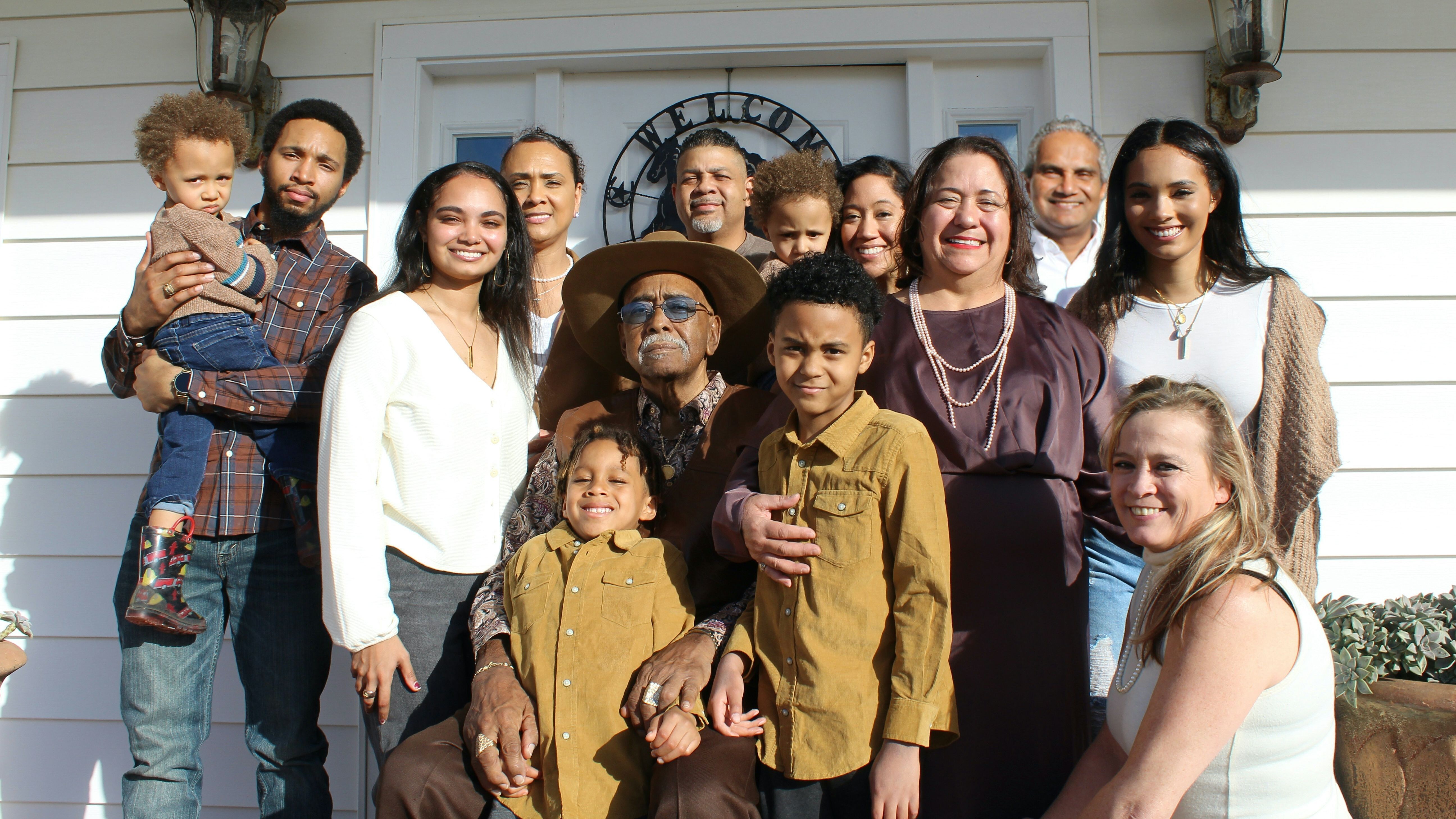 A multigenerational family poses for a portrait on a front porch
