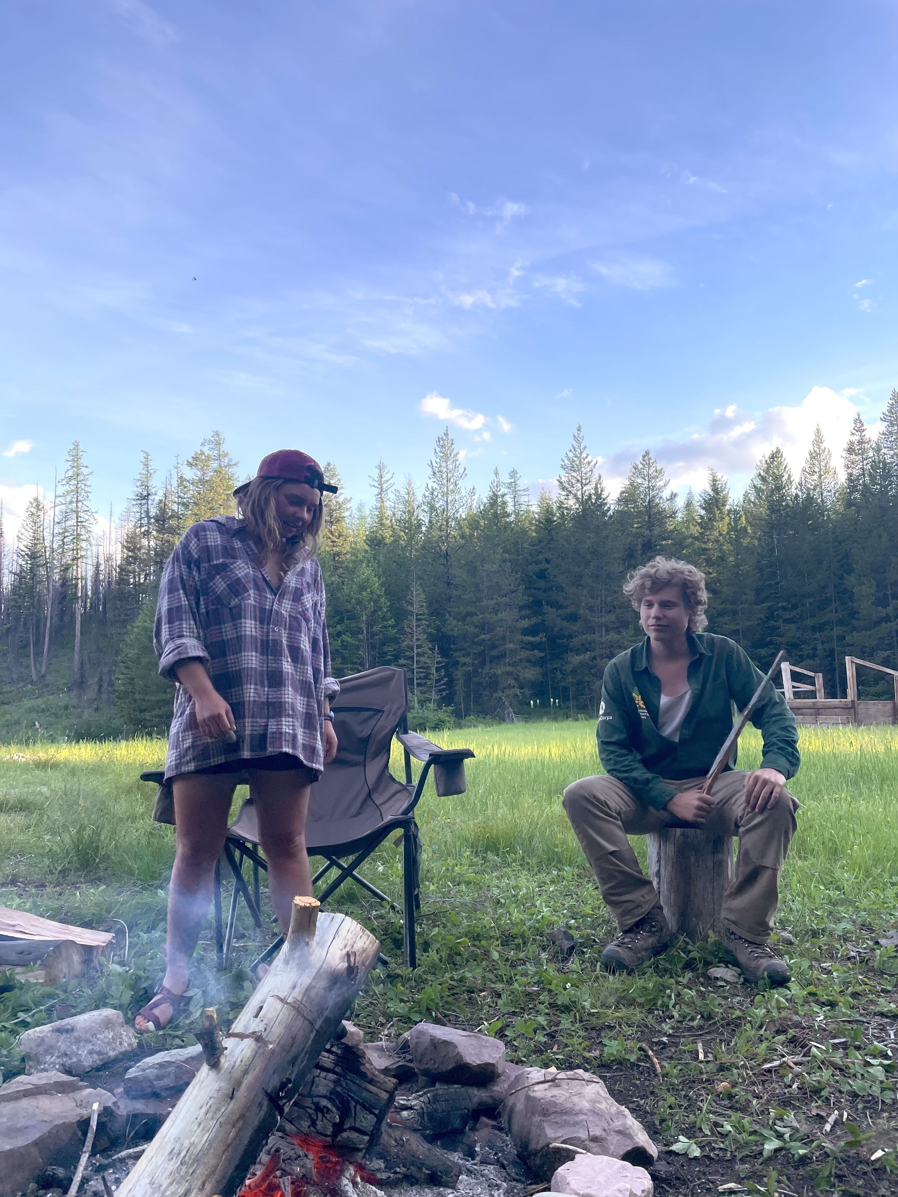 Two crew members sit around a fire, enjoying their end of day.