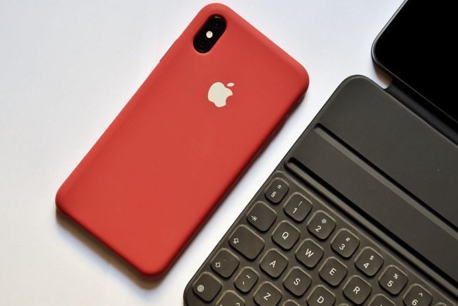 An iPhone in a red case and an iPad in a black keyboard case.