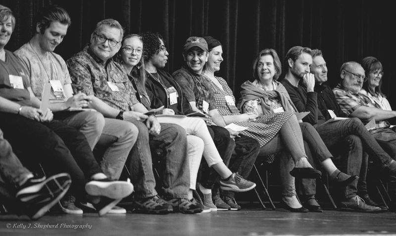 A line of PSC patients and caregivers sit on stage at a PSC Partners conference.