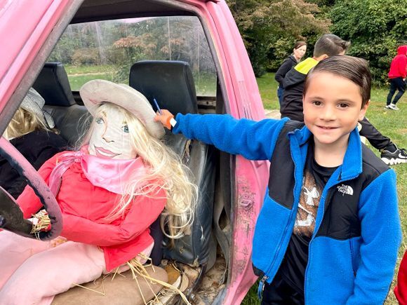 A young girl touches the hat of a Barbie scarecrow at Snipes Farm Fall Festival