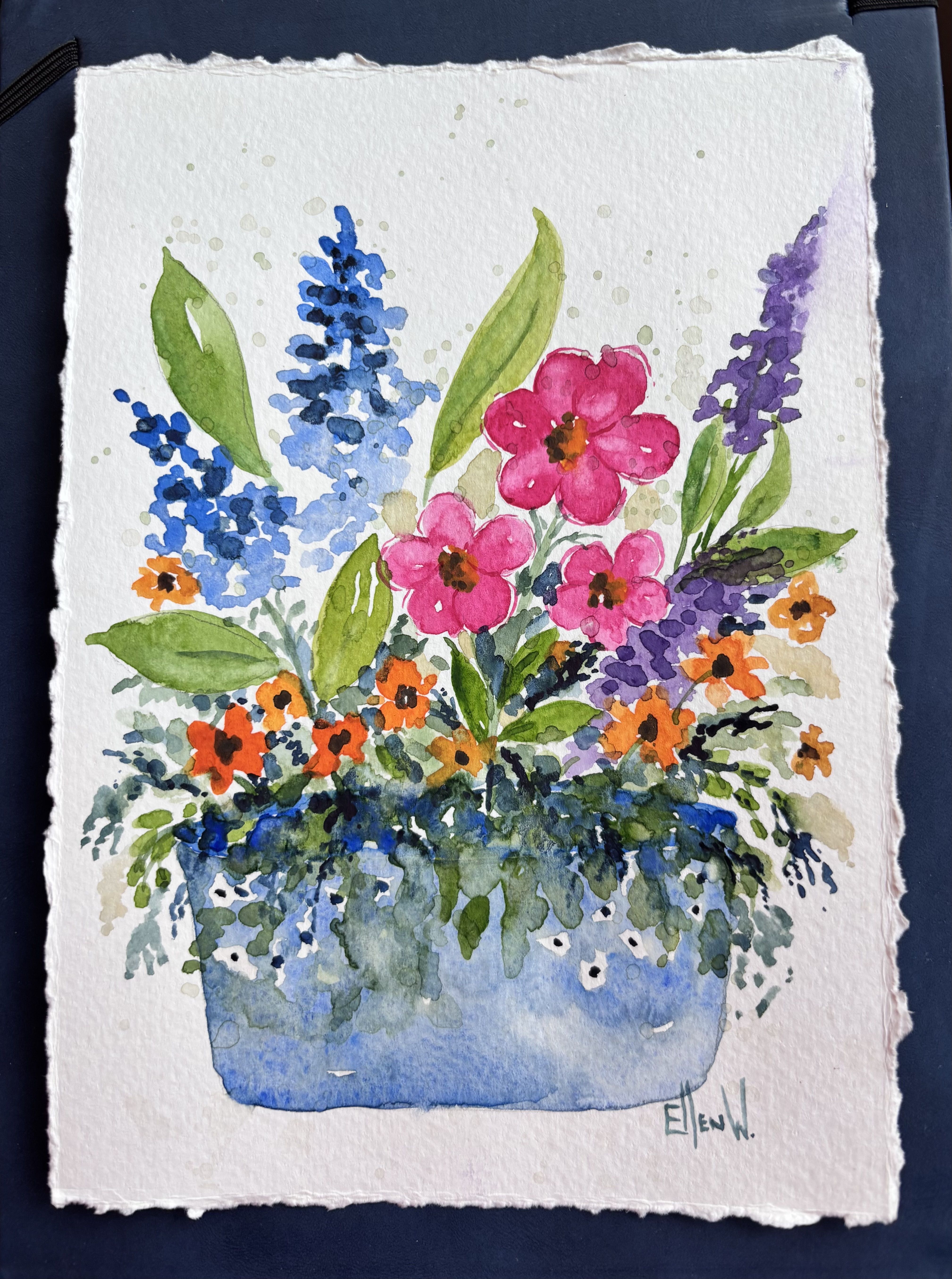 Pink, blue, purple, and orange wildflowers blooming in a large, blue pot.