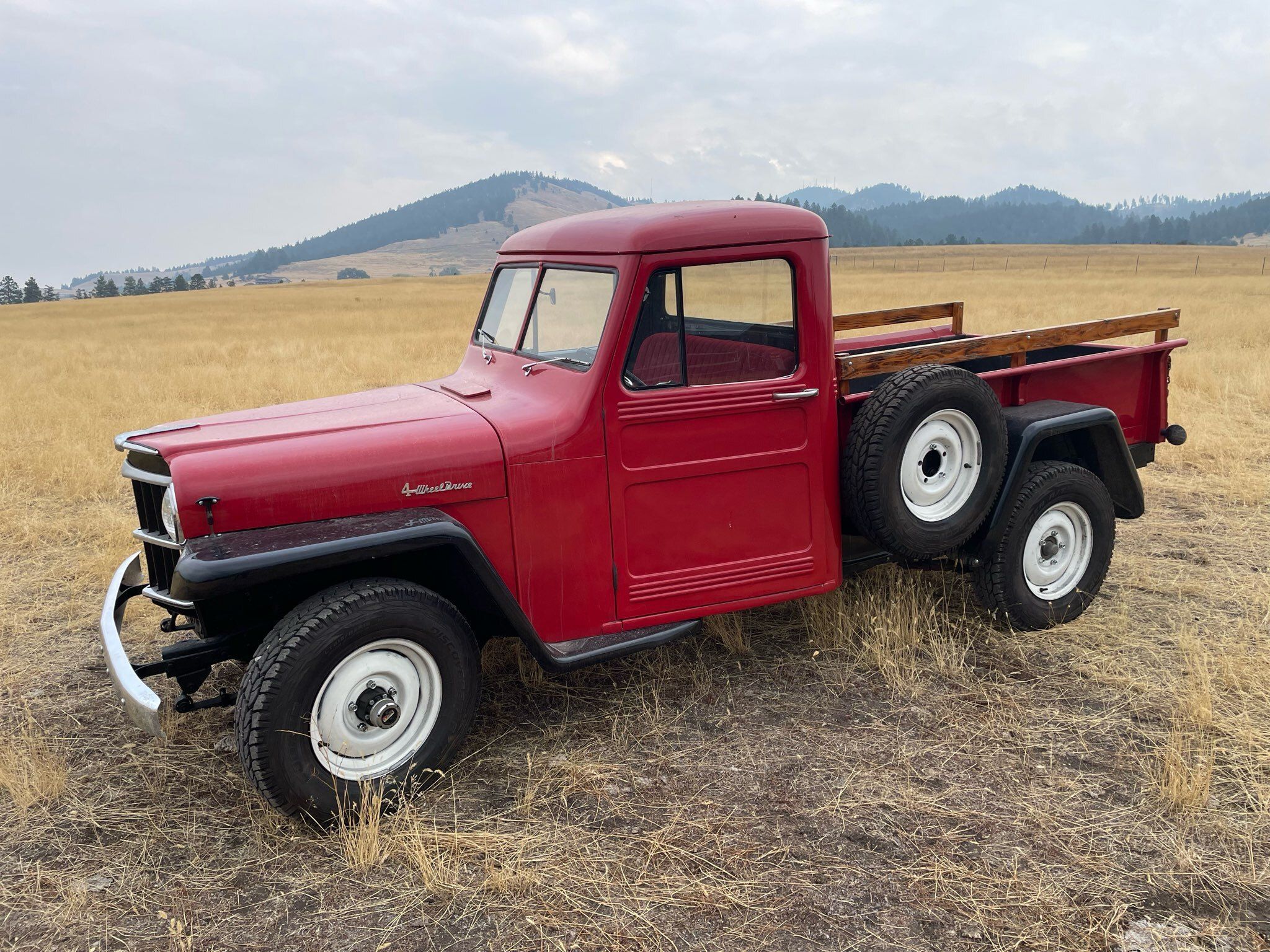 Vintage red gardening truck parked in a field.