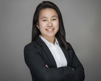 Asian woman with long black hair, black blazer, and white collared shirt smiling.