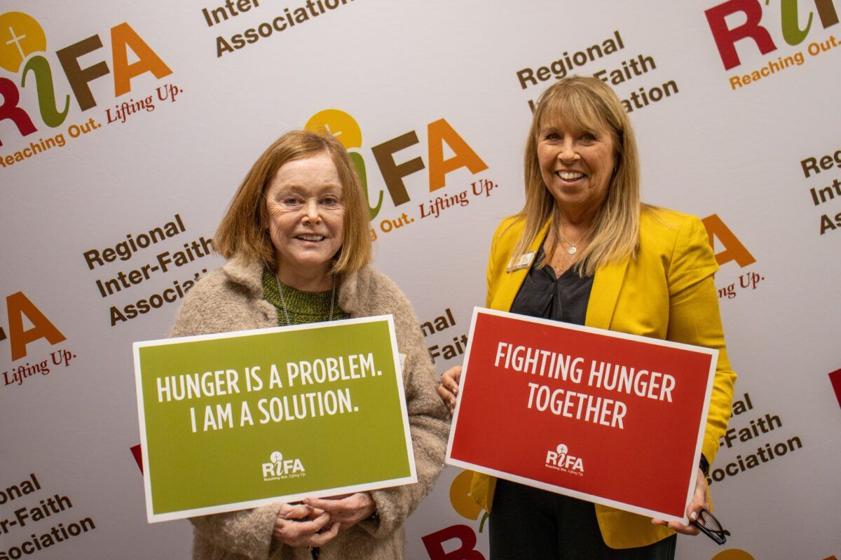 Two women holding signs about fighting hunger