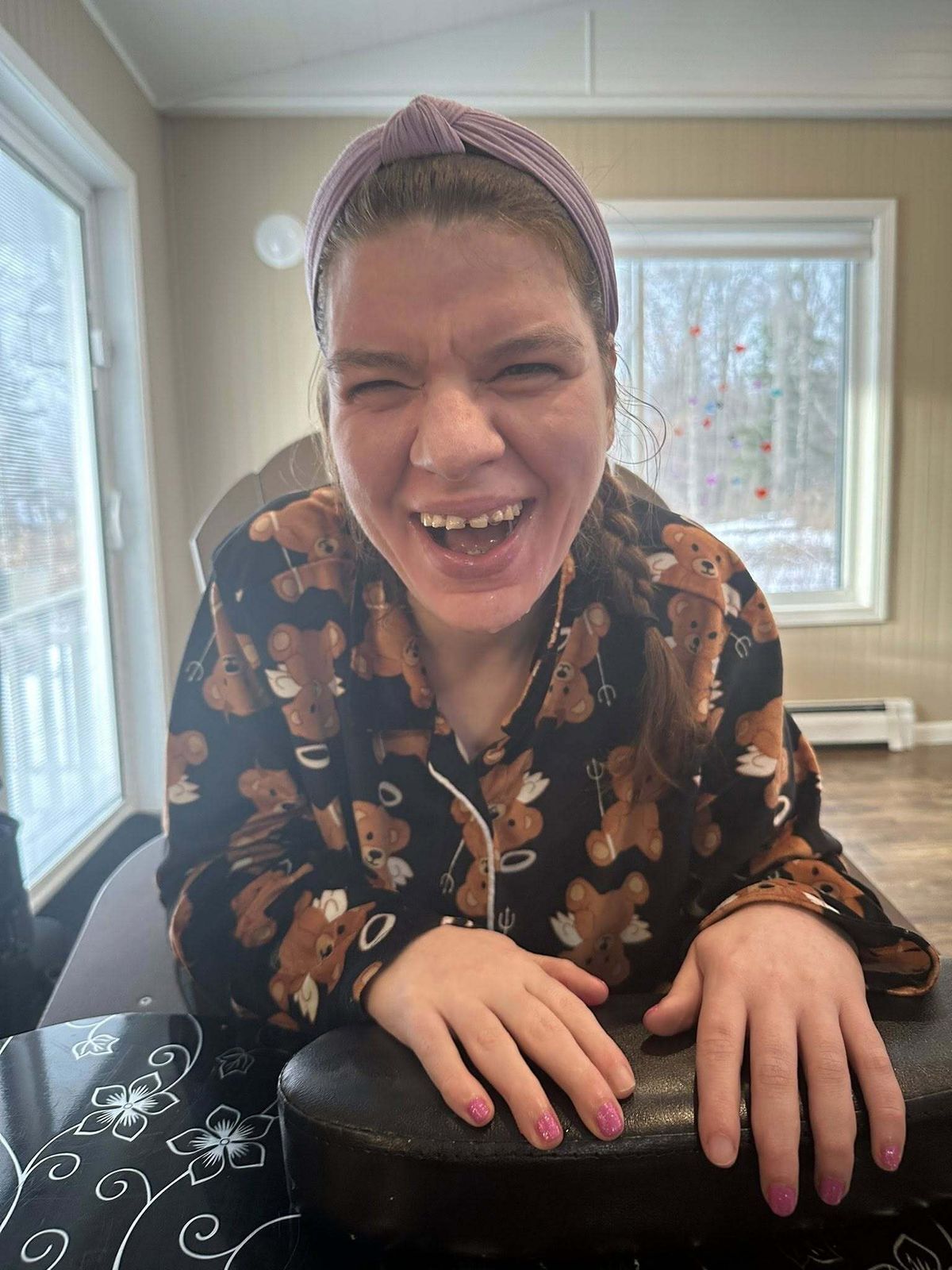 A young woman faces the camera laughing, her hands facing out with her nails being painted.)